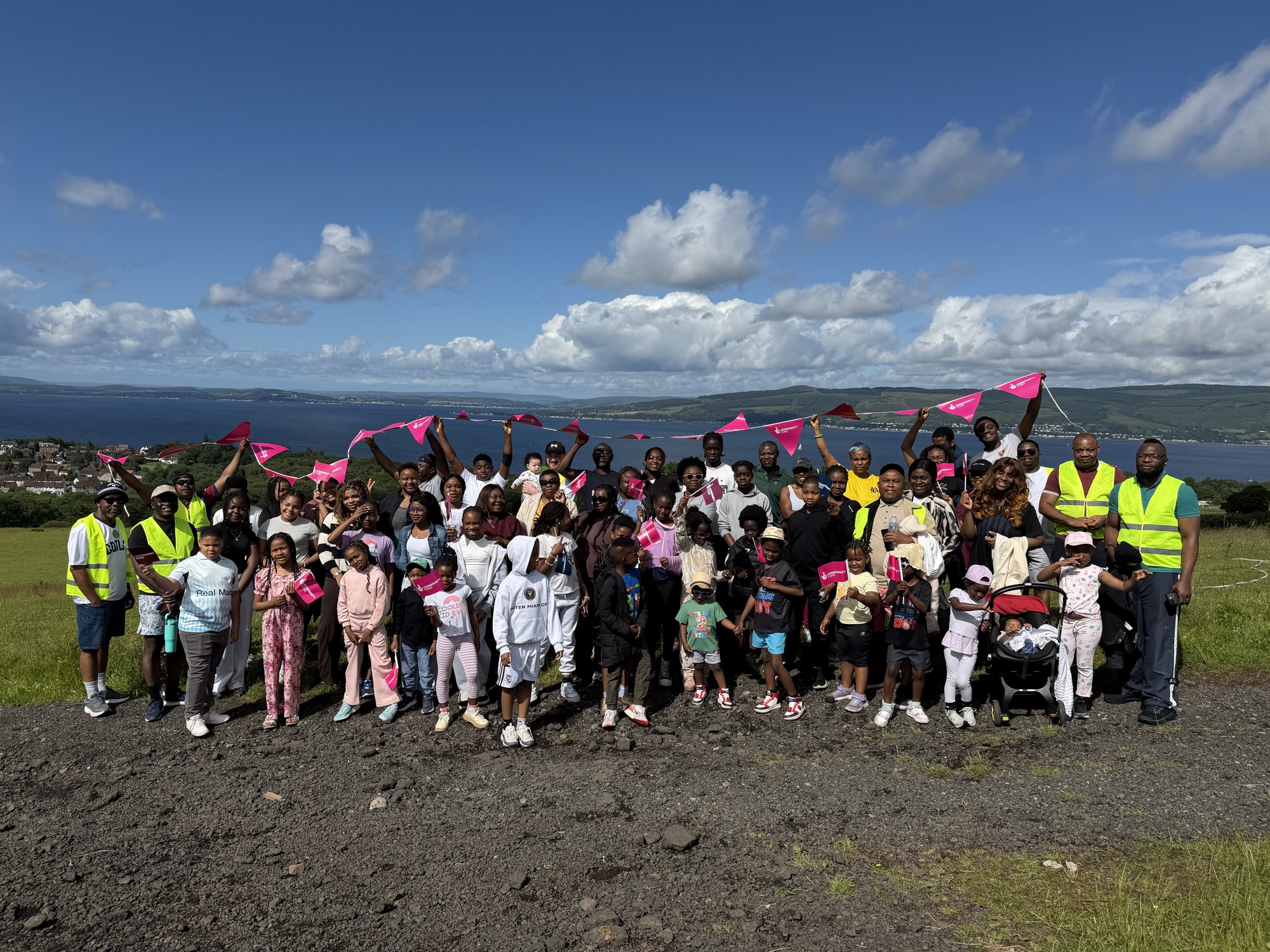 Around a hundred members of the Nsukka community in Glasgow gathered on a hilltop above Wemyss Bay, waving pink flags, with the Firth of Clyde behind them
