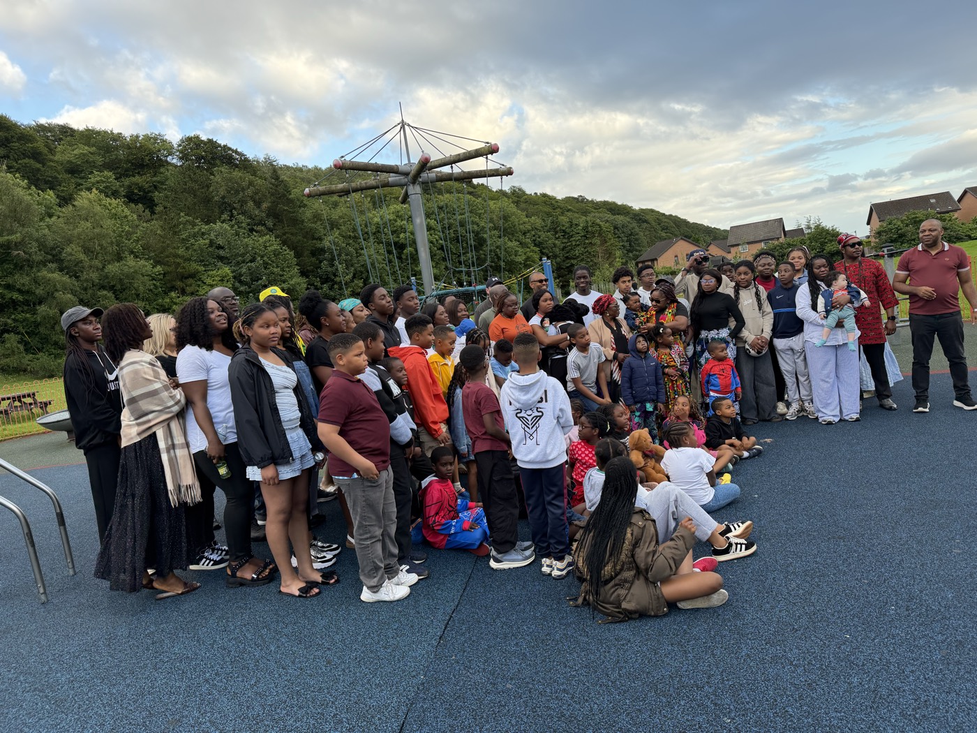 Families gathered in the park playground under a bright sky