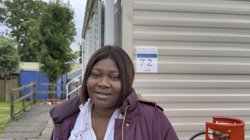 A member standing outside her caravan