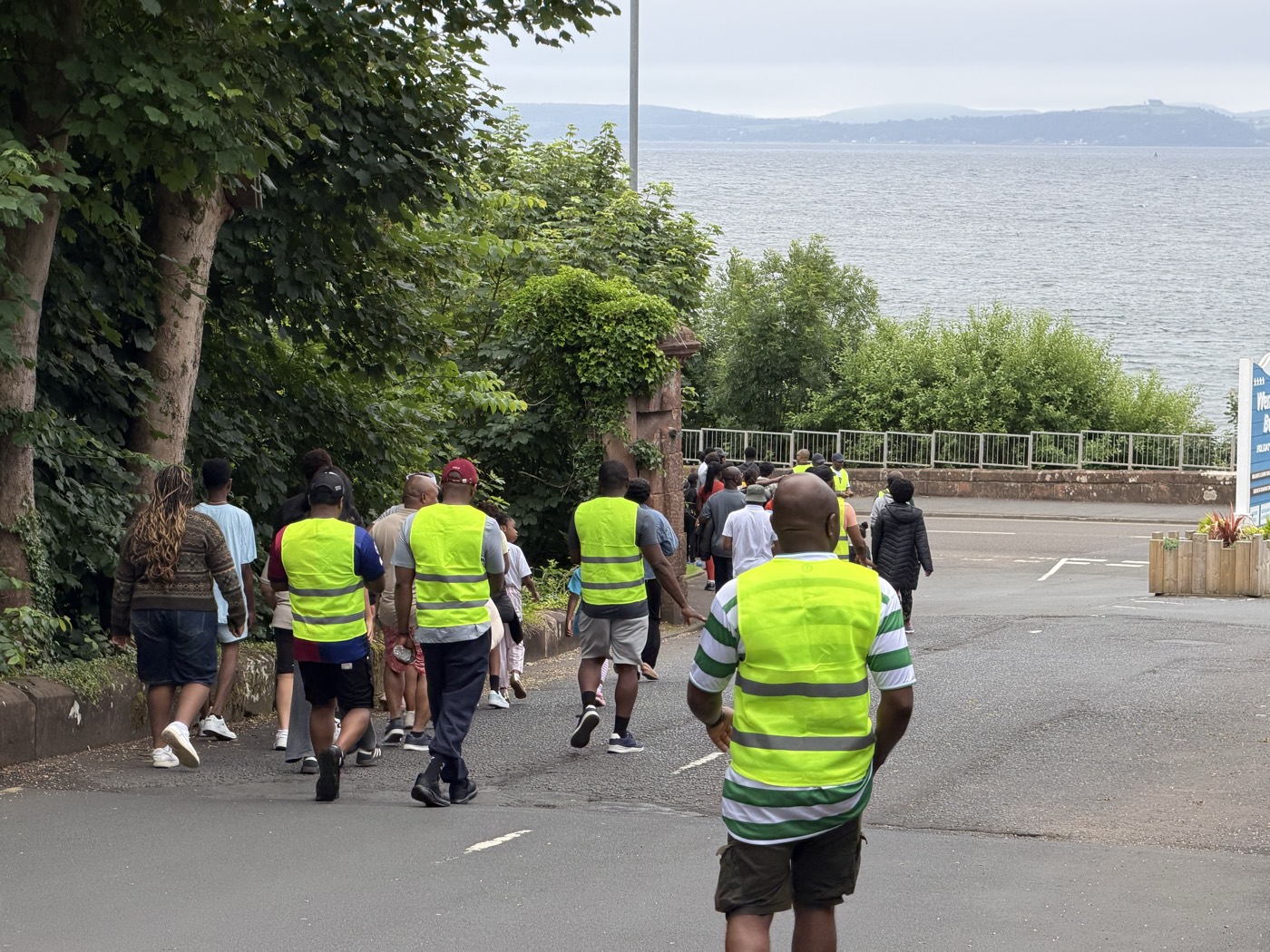 Walkers in hi-vis vests heading down to the seafront, the Clyde visible through the trees